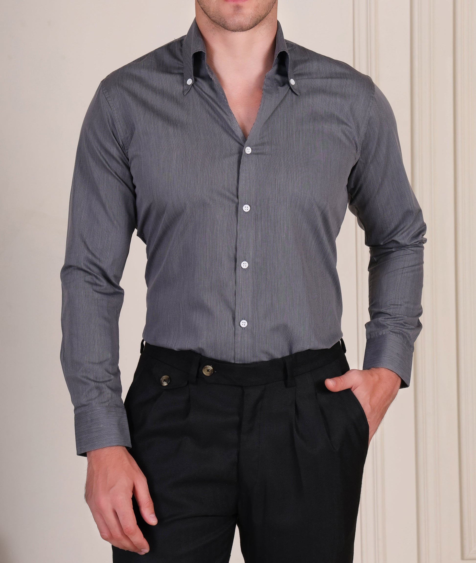 Man wearing a gray italian vega shirt and black gurkha pants against a neutral background